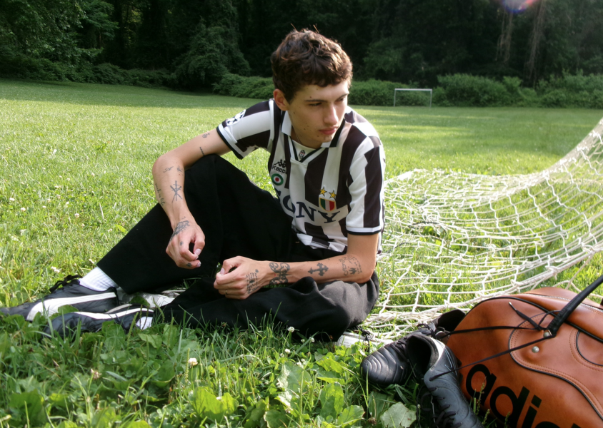 Musician Glaive sitting in front of football goals wearing a football top.x